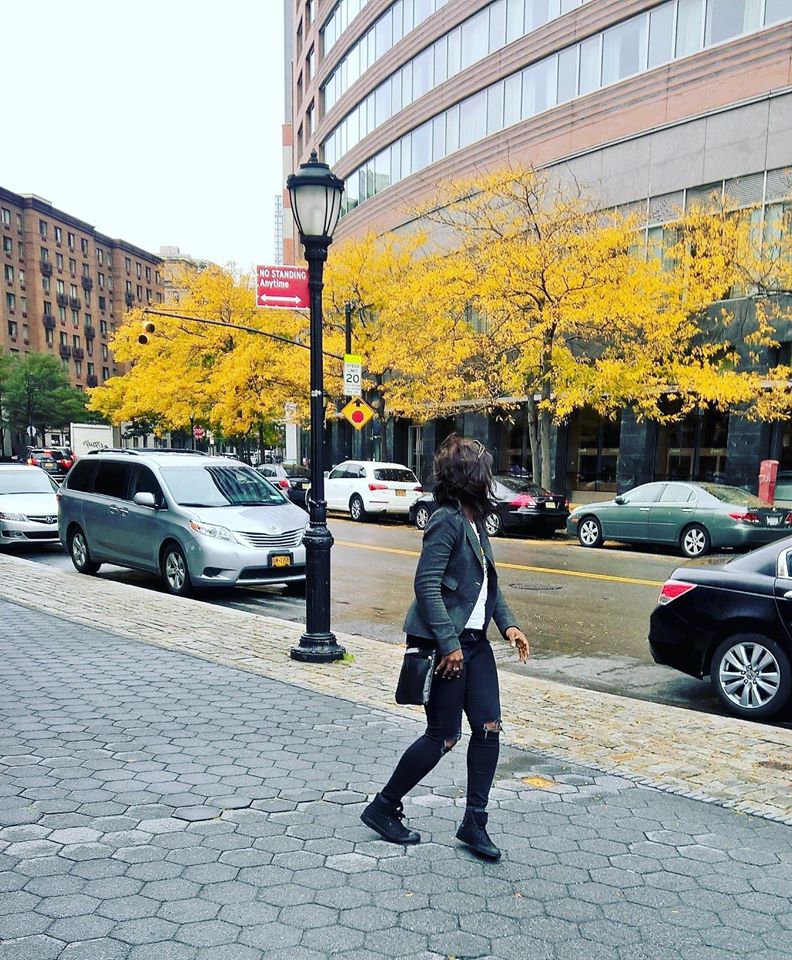 Ommo Clark walking on a cobblestone street in lower Manhattan, New York, 2016, with autumn ginkgo trees in the background